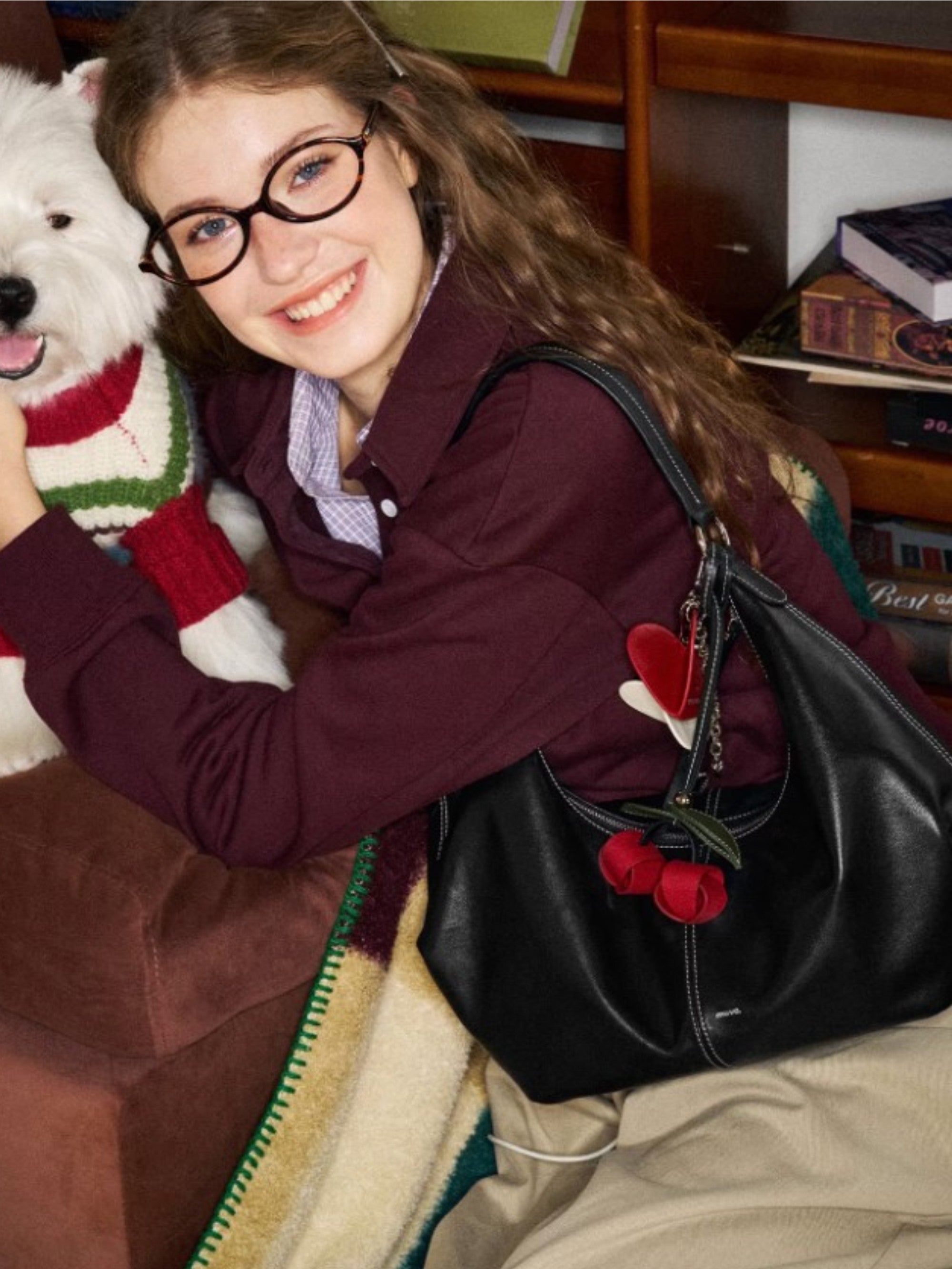 Breloque de sac Cerise tissée MUVA accrochée à un sac noir en situation.
