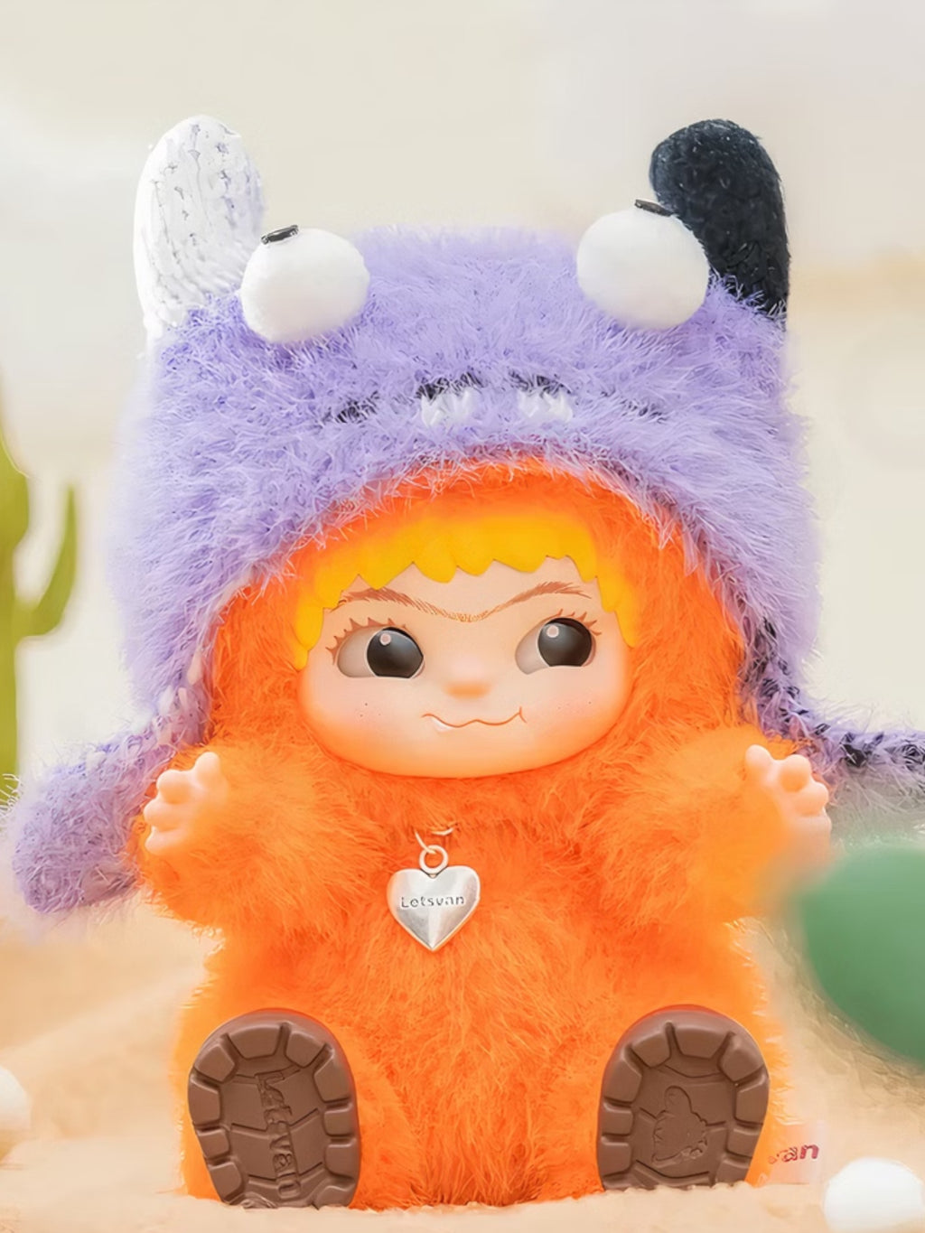 Wakuku figurine chibi – personnage orange costume capuche violet oreilles rondes, assis, fond blanc
