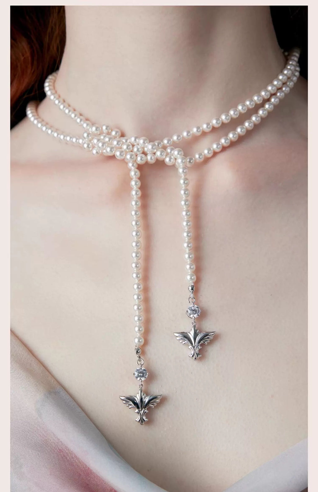 Gros plan d’un collier perles en choker avec double pendentif argenté