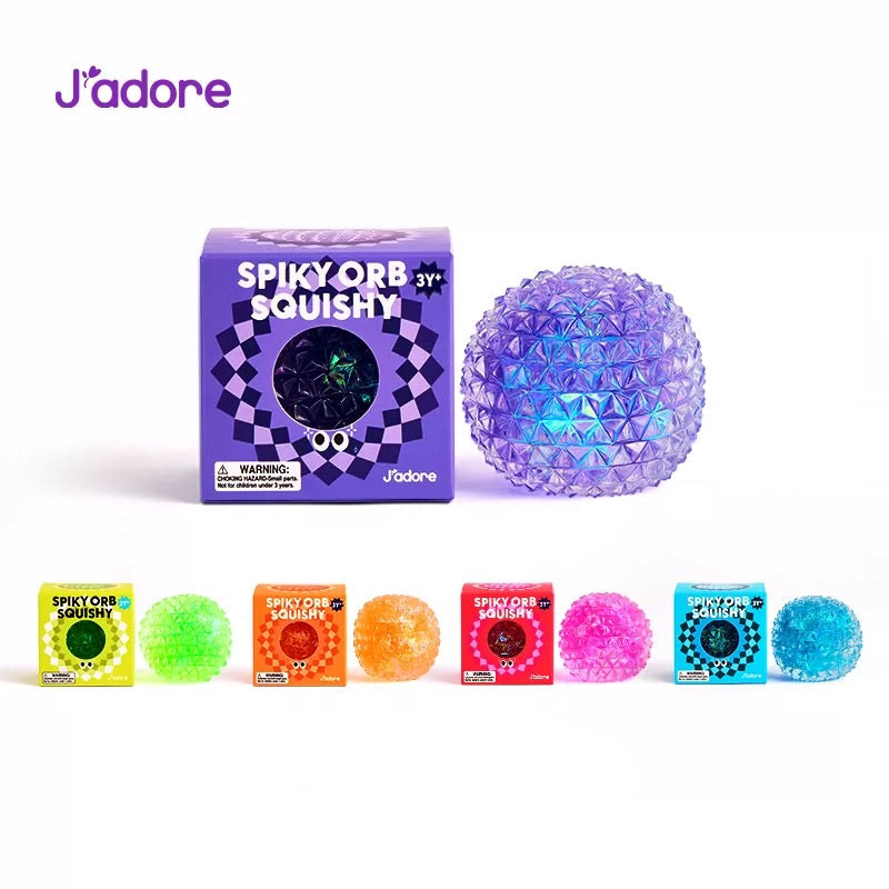 Collection complète J'adore Spiky Orb Squishy : grand format violet irisé avec sa boîte, et les 5 coloris en petit format — vert fluo, orange, rose fuchsia et bleu — avec leurs boîtes d'emballage, photo produit sur fond blanc
