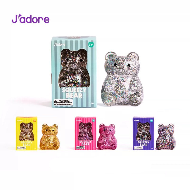 Collection complète J'adore Squeezy Bear gel pailleté : grand format argent avec boîte rayée bleue, et 3 coloris petit format — doré, rose et violet — avec leurs boîtes, photo produit sur fond blanc
