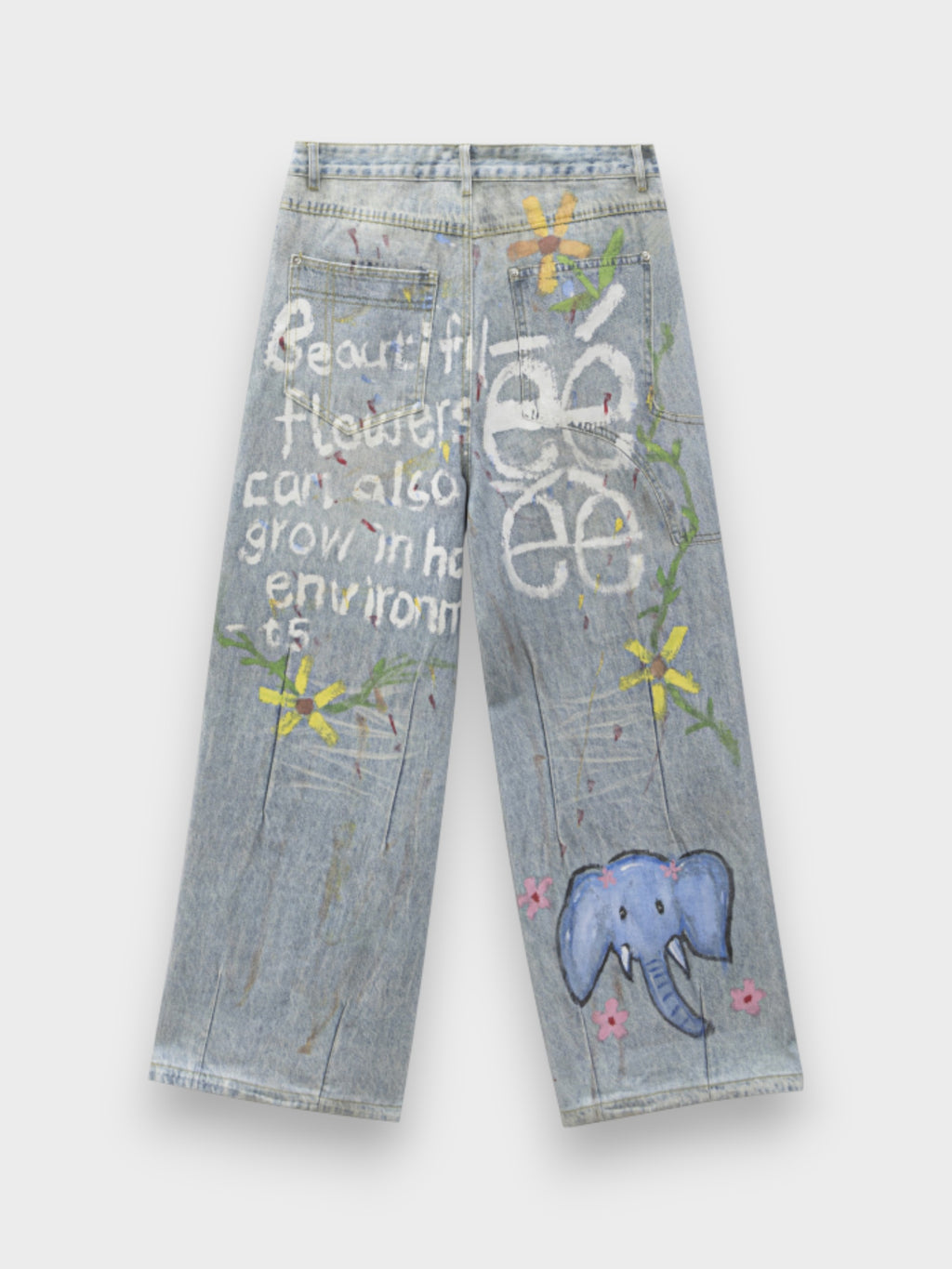 Jean large eeee Artmonster bleu clair avec prints graffiti éléphant bleu, fleurs jaunes et texte "Beautiful flowers can also grow in hard environments", vue de dos sur fond gris
