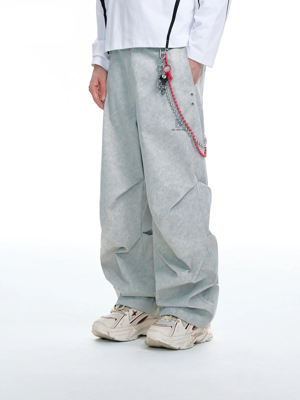 Pantalon large BJHG gris avec chaîne argentée et rouge à breloque boule 8, porté par un homme avec sneakers blanches, vue de face sur fond blanc
