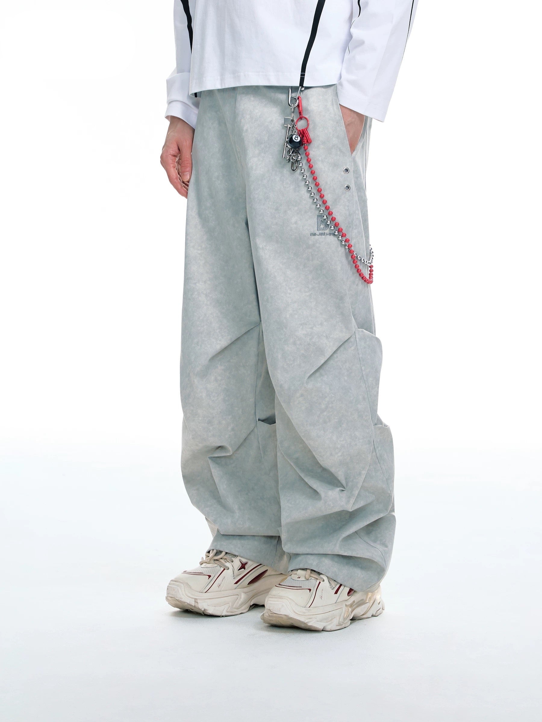 Pantalon large BJHG gris avec chaîne argentée et rouge à breloque boule 8, porté par un homme avec sneakers blanches, vue de face sur fond blanc
