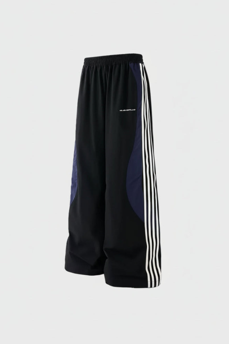 Pantalon BJHG noir et marine bicolore large à bandes blanches, vue de profil sur fond gris
