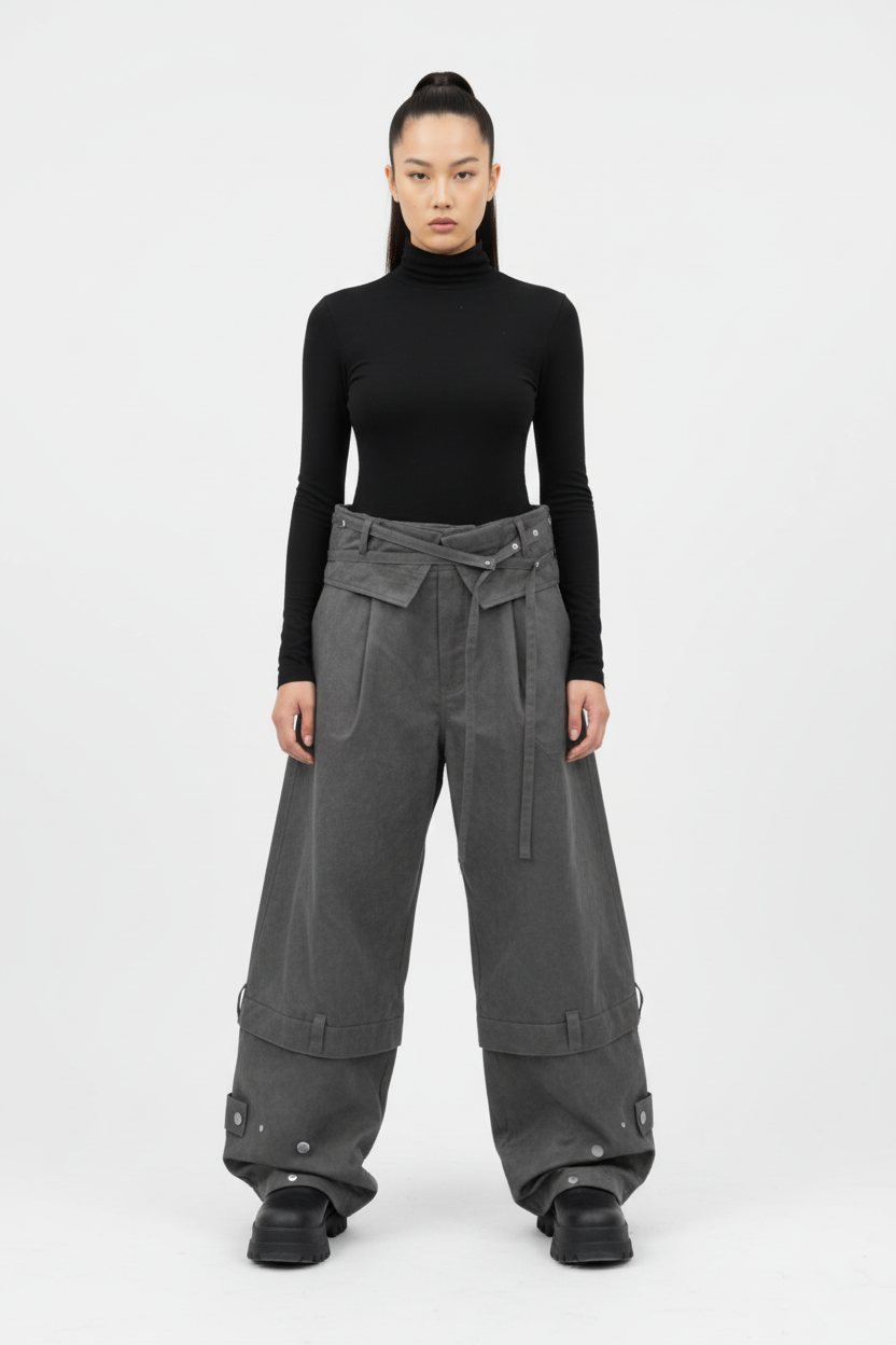 Pantalon cargo RELABEL gris large à ceinture lacets et poches cargo avec rivets, porté par une femme avec col roulé noir, vue de face sur fond blanc
