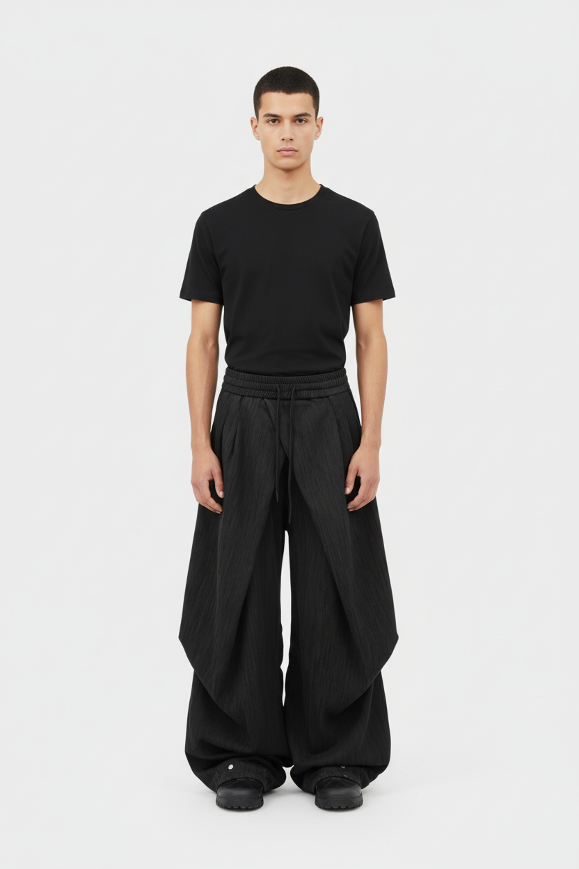 Pantalon RELABEL noir extra large à grands plis taille basse, porté par un homme avec t-shirt noir, vue de face sur fond blanc
