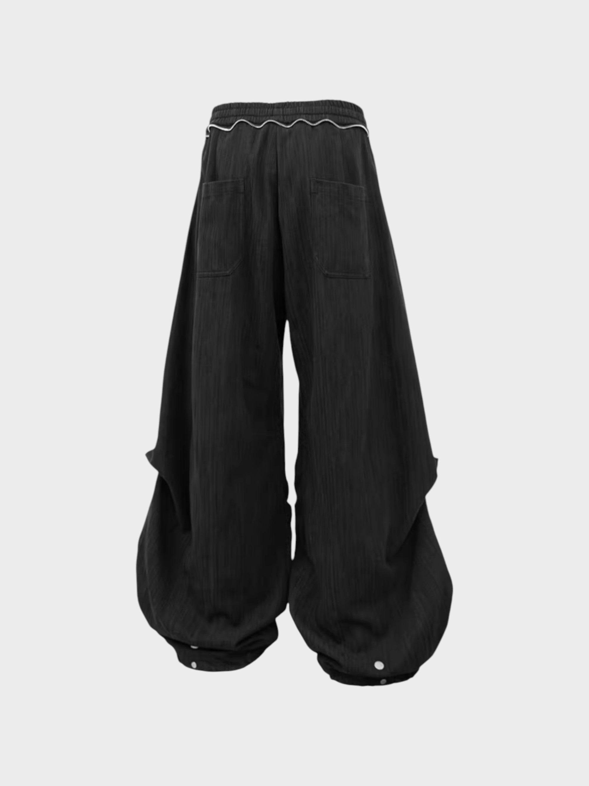 Pantalon sarouel RELABEL noir large à liseré blanc en ceinture et poches dos, pression cheville, vue de dos sur fond gris
