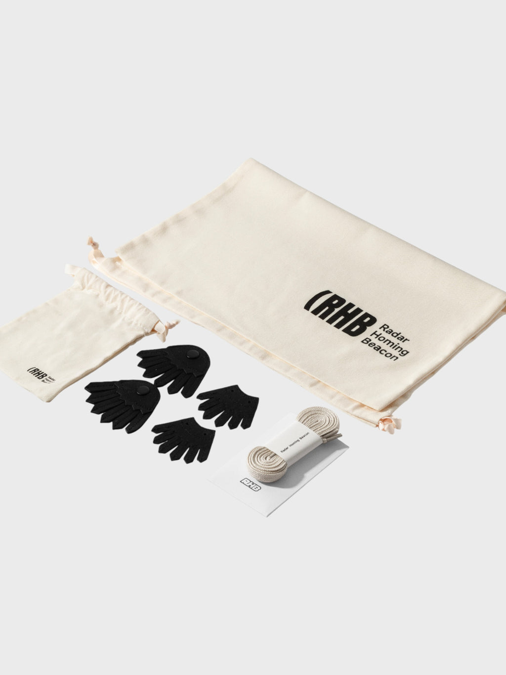 Radar Homing Beacon RHB kit complet – 4 paires de chaussettes orteils noires, lacets coton beige enroulés, grande pochette coton écru logo RHB et petite pochette coton, fond blanc
