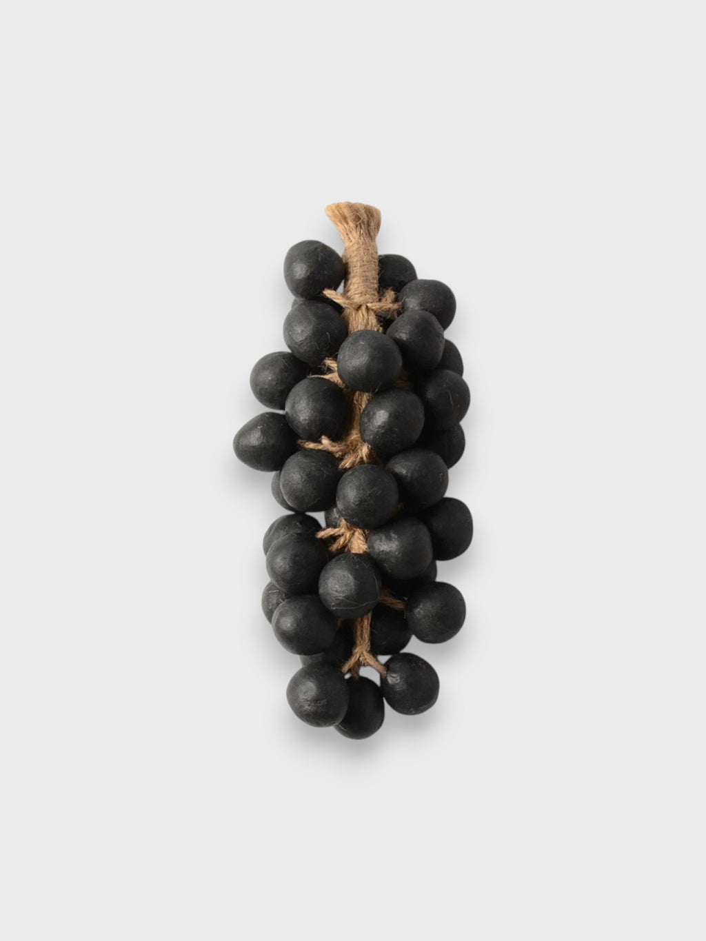 Savons DIOIB en forme de grappe de raisin noir et beige sur plan en marbre blanc, salle de bain lumineuse avec baignoire et plantes vertes
