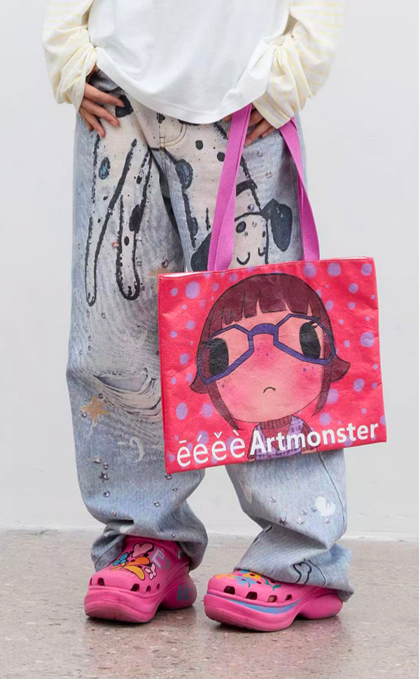 Tote bag eeee Artmonster rouge avec print manga kawaii fille à lunettes et pois, anses roses, porté à la main avec jean large print chiens et crocs roses
