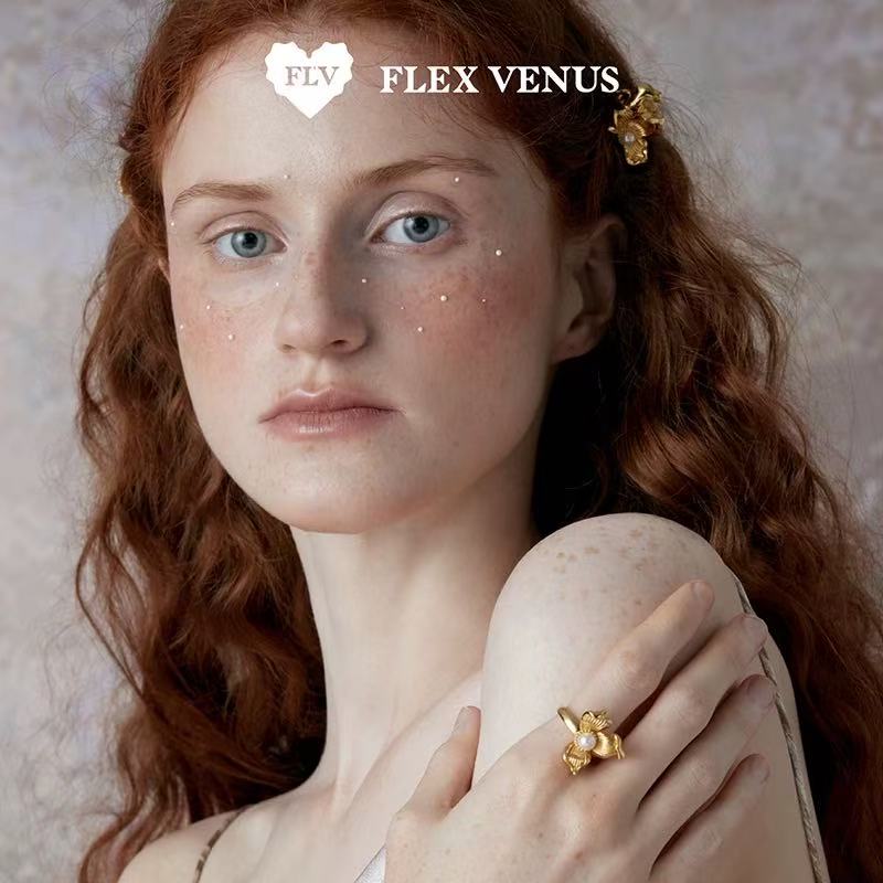 Gros plan de bague fleur dorée sculpturale avec perle, portée au doigt