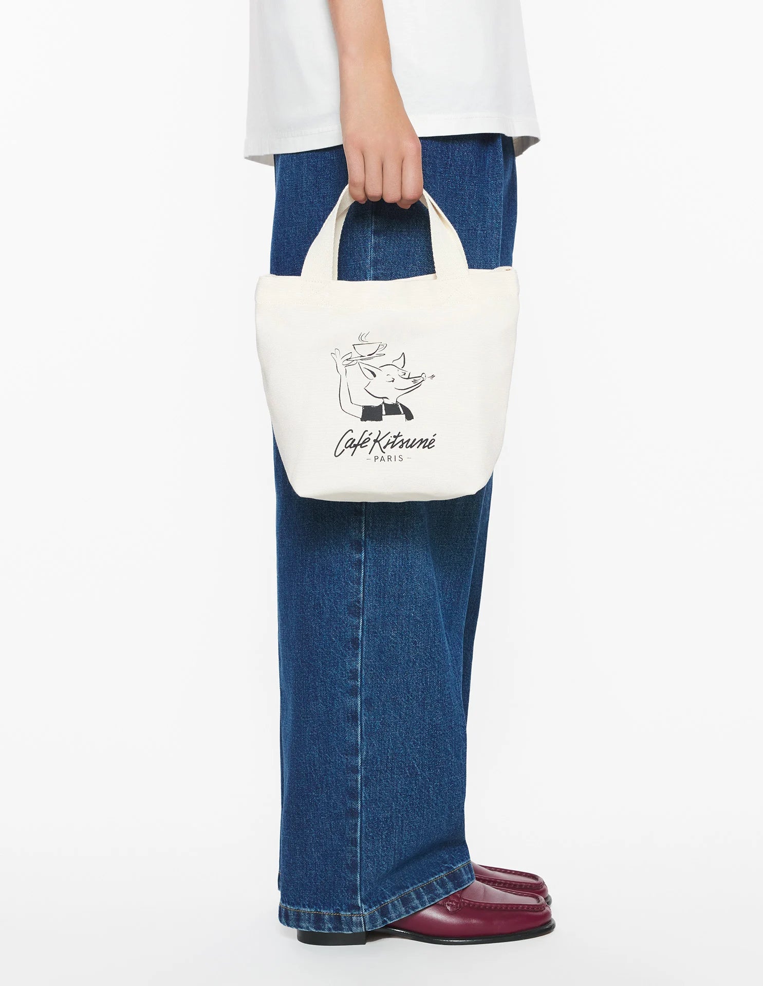 Sac tote Café Kitsuné blanc porté à la main, style lifestyle urbain