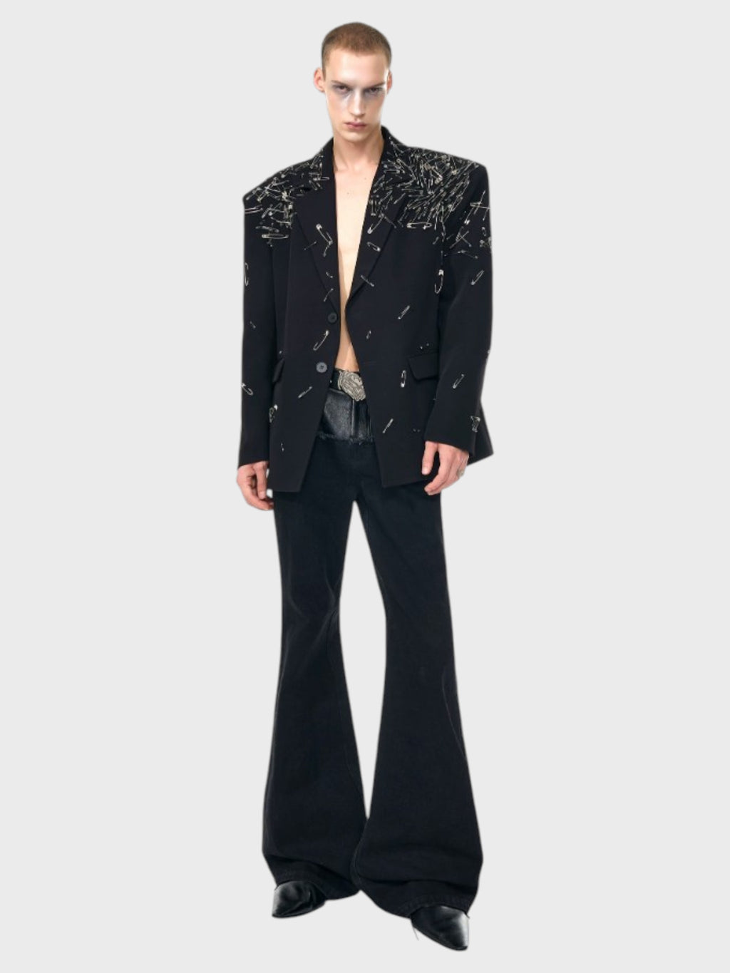 Blazer oversize STARTEXCEEDEND noir épingles de sûreté porté par un homme torse nu, look complet avec pantalon bootcut noir et boots noires, vue de face
