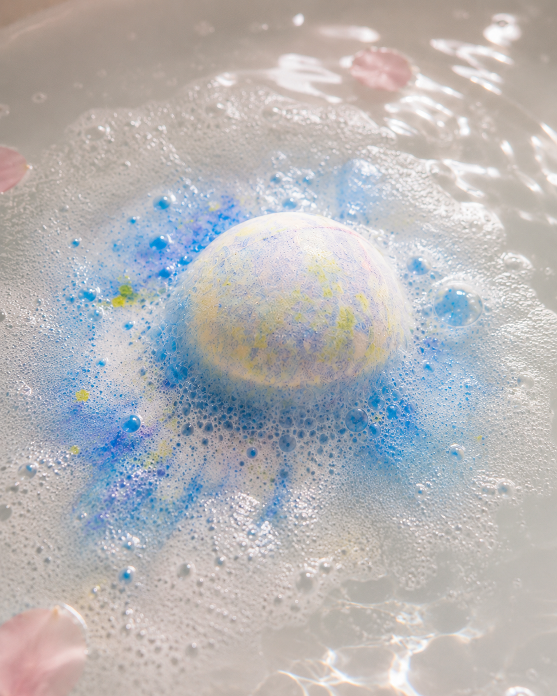 Bombe de bain artisanale bleue et jaune en bicarbonate en dissolution dans le bain, en utilisation