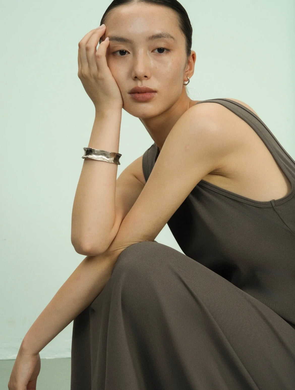 Bracelet jonc martelé Freddo argenté en argent sterling, porté par une femme assise en studio, vue de côté