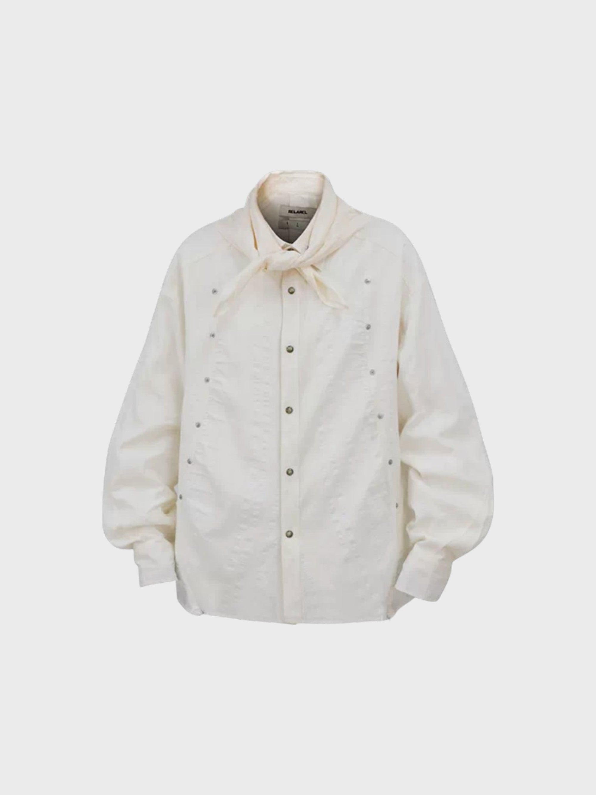 Chemise oversize RELABEL blanc cassé avec col foulard noué, rivets argentés all-over et boutons-pression, vue de face
