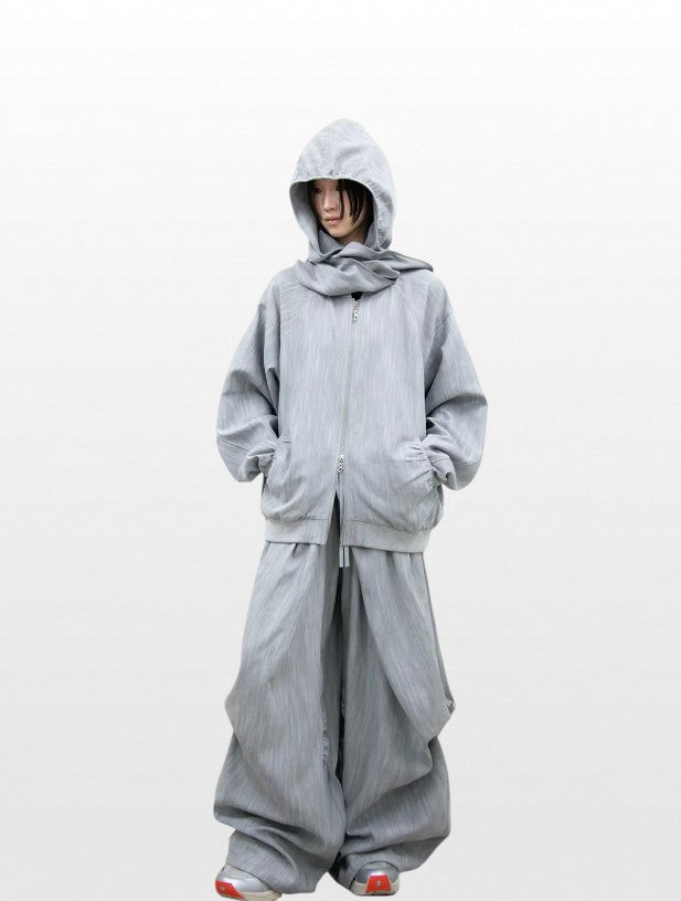 Hoodie zip capuche oversize RELABEL gris chiné porté par une femme, capuche relevée, look complet avec jogging large gris assorti et sneakers rouges
