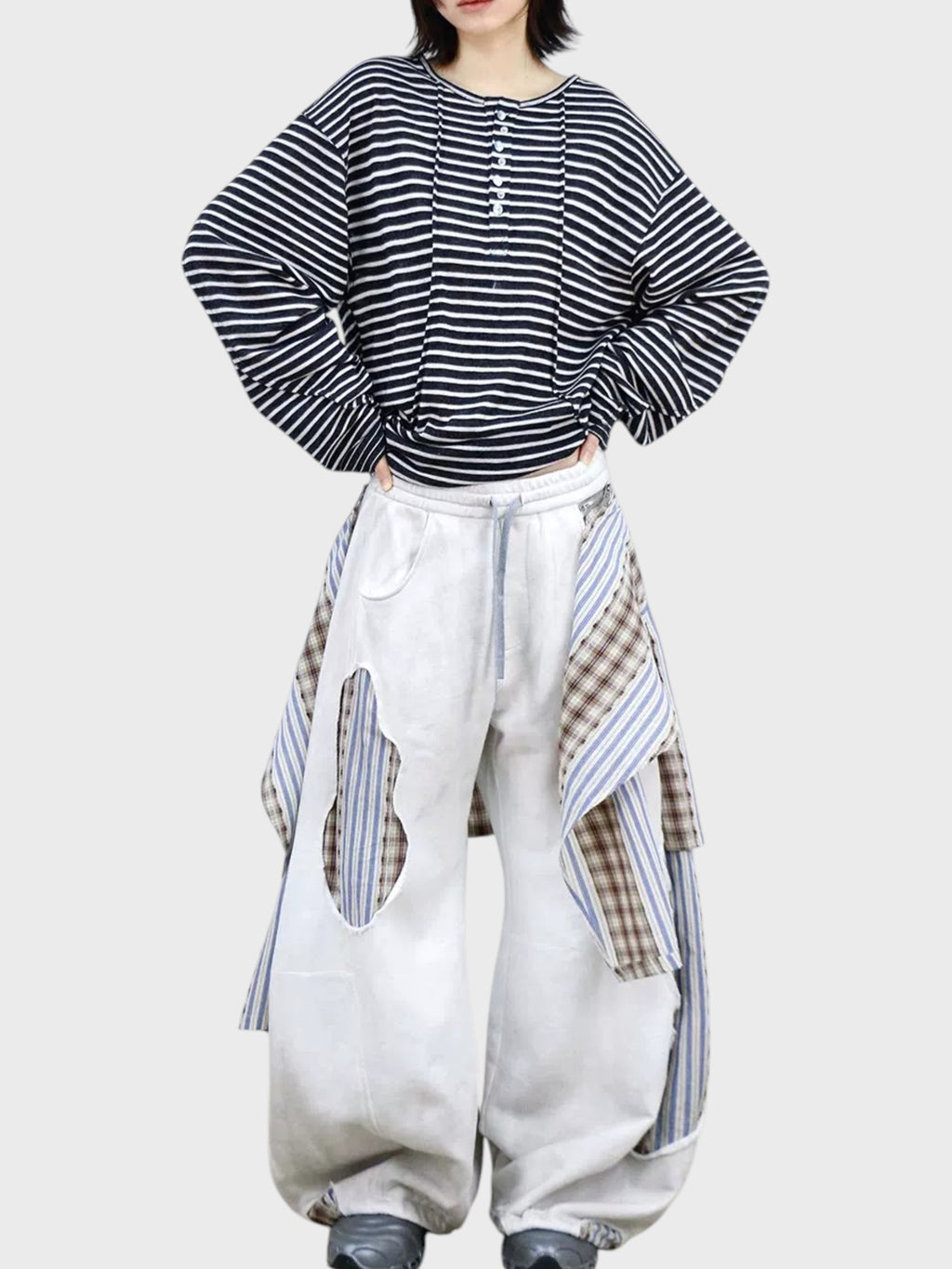 Jogging large RELABEL blanc patchwork porté par une femme, vue de face avec t-shirt rayé marine et chaussures grises
