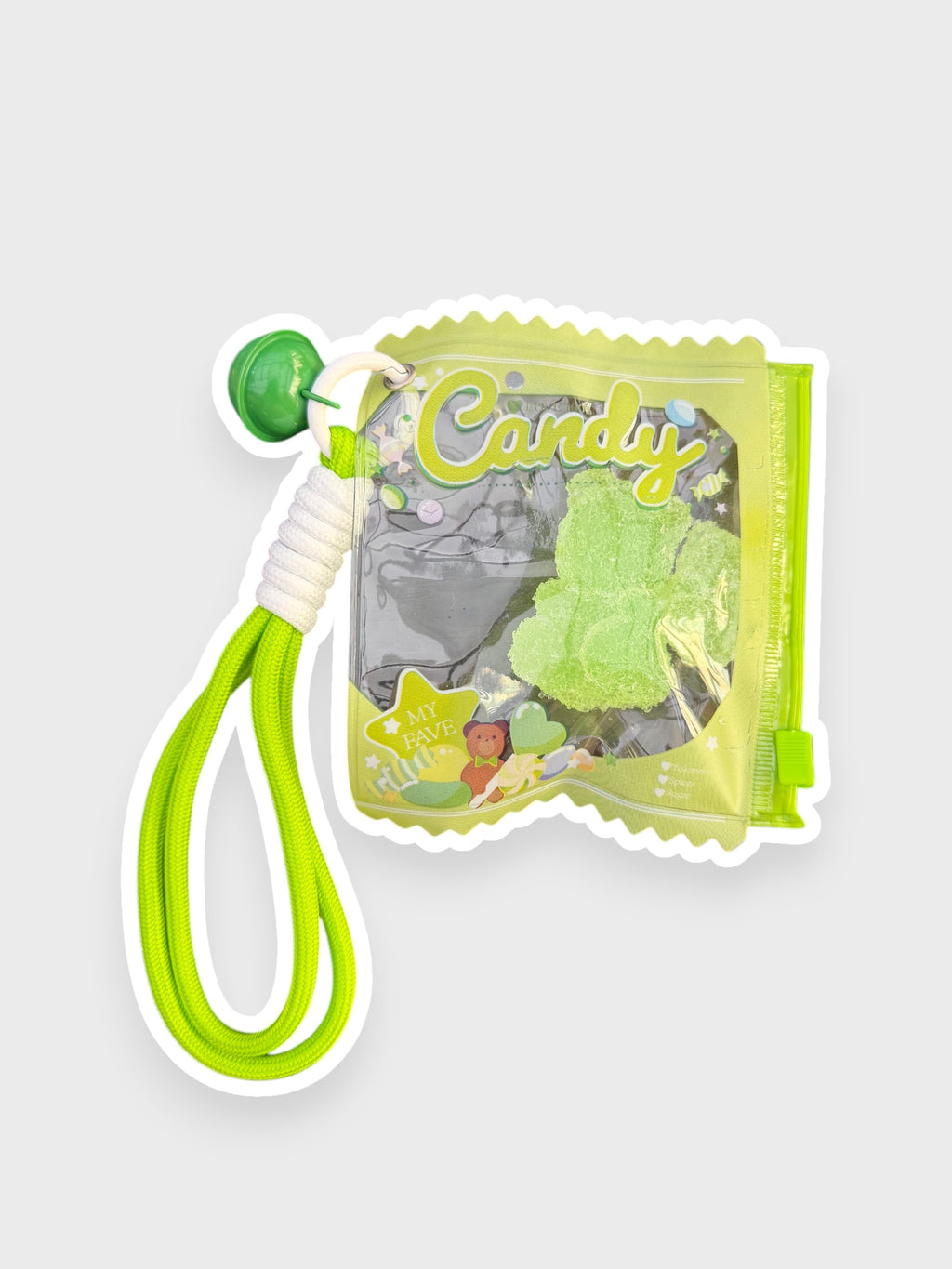Jouet anti-stress ourson gélifiant pomme verte recouvert de sable scintillant vert givré dans sachet transparent vert anis forme bonbon Candy lettrage vert olive avec lanterne cordon vert fluo et grelot vert, fond gris