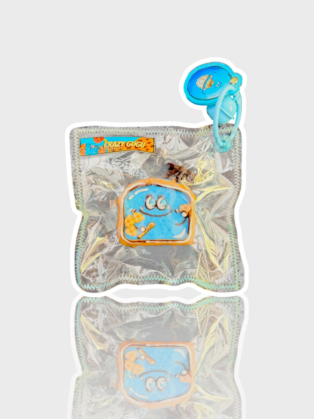 Jouet squishy mousse souple Crazy Gugu bleu polyuréthane, vue de face dans emballage holographique