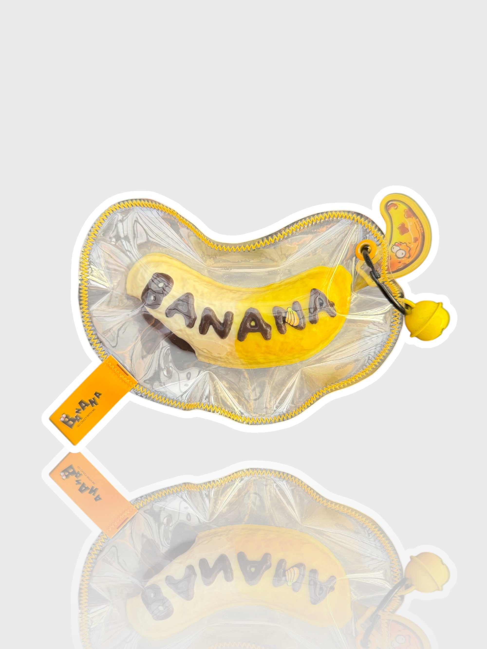Jouet squishy mousse souple Crazy Gugu jaune polyuréthane banane B-AANA, vue de face dans emballage zippé transparent fond blanc
