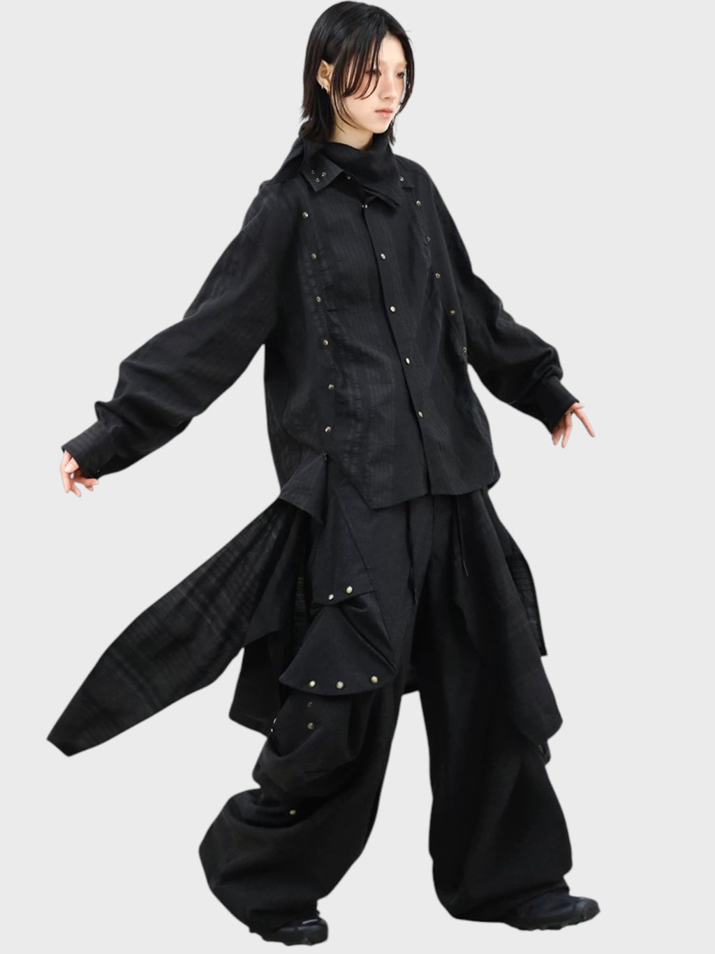 Pantalon déconstructiviste RELABEL noir porté par une femme de profil, avec veste noire boutons-pression et poches cargo déployées
