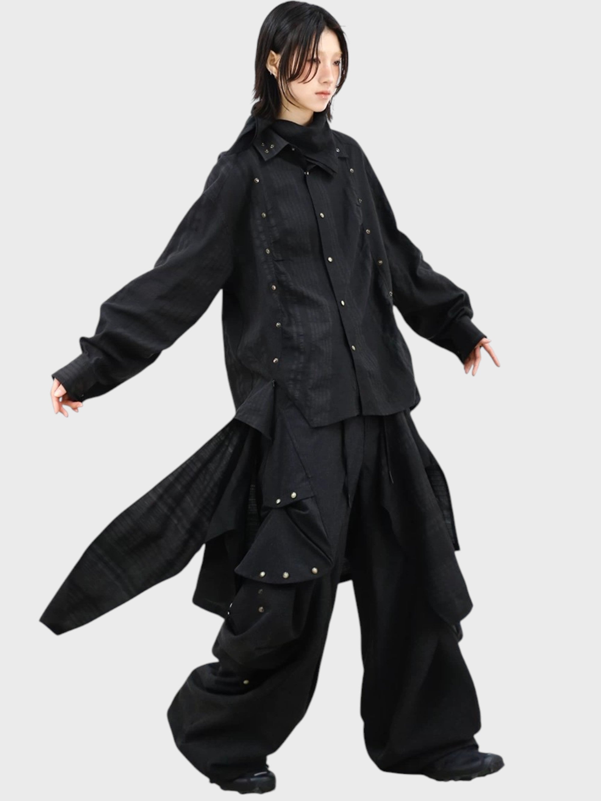 Pantalon déconstructiviste RELABEL noir porté par une femme de profil, avec veste noire boutons-pression et poches cargo déployées
