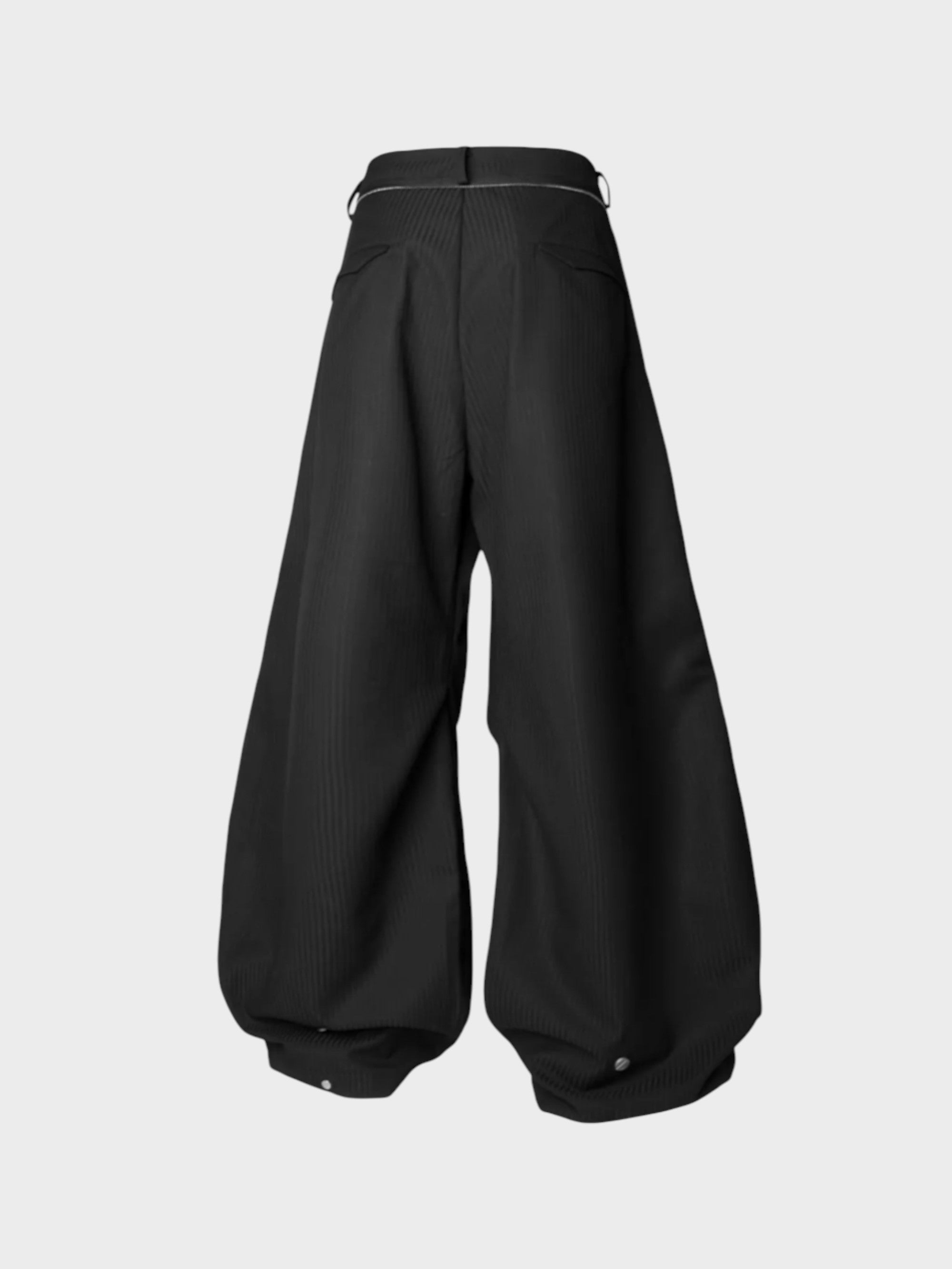 Pantalon ballon plissé asymétrique Relabel noir en laine, vue de dos sur fond gris, détail anneau métal et boutons-pression