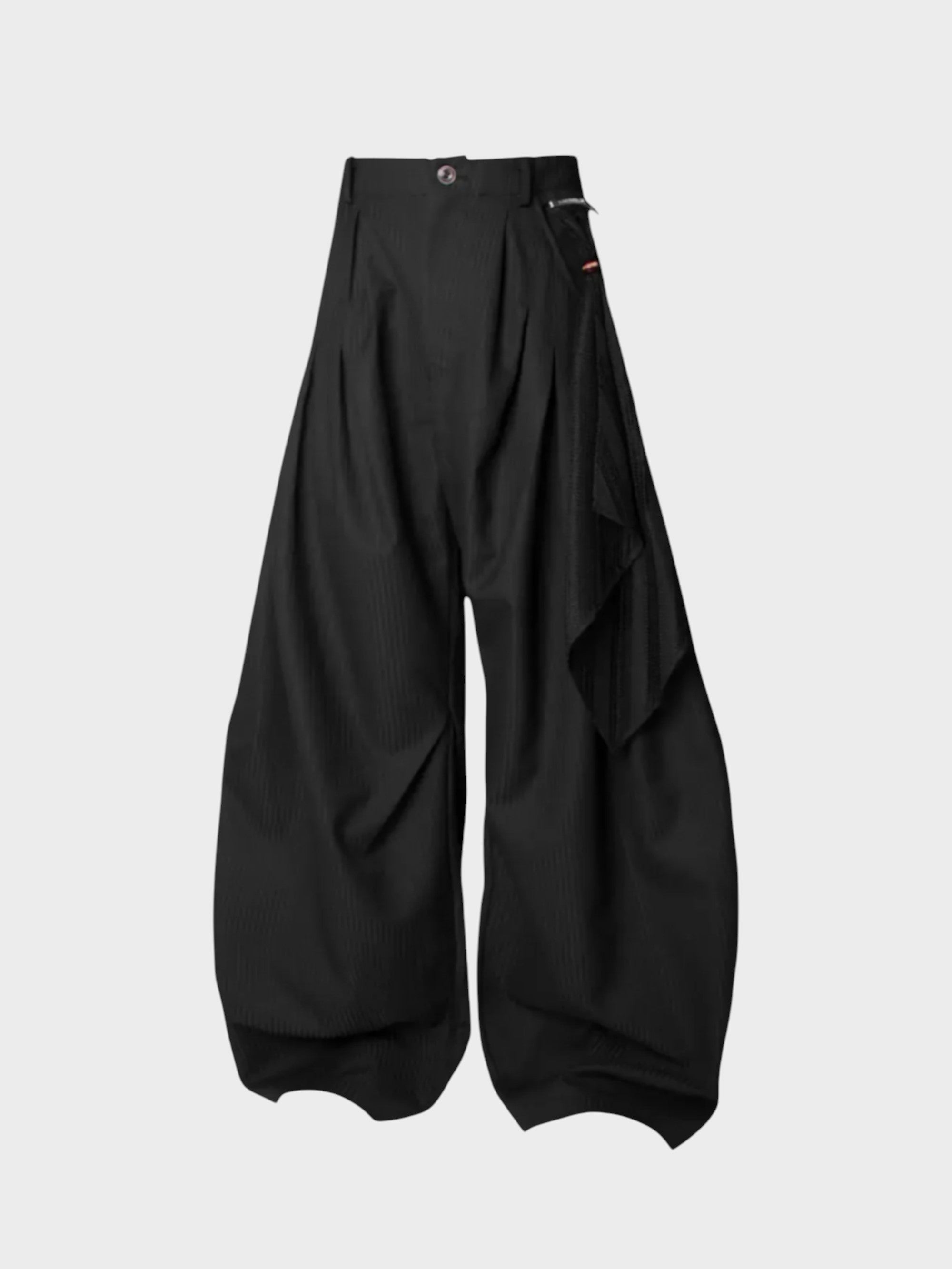 Pantalon ballon plissé asymétrique Relabel noir en laine, vue de face sur fond gris, détail bouton et étiquette tricolore