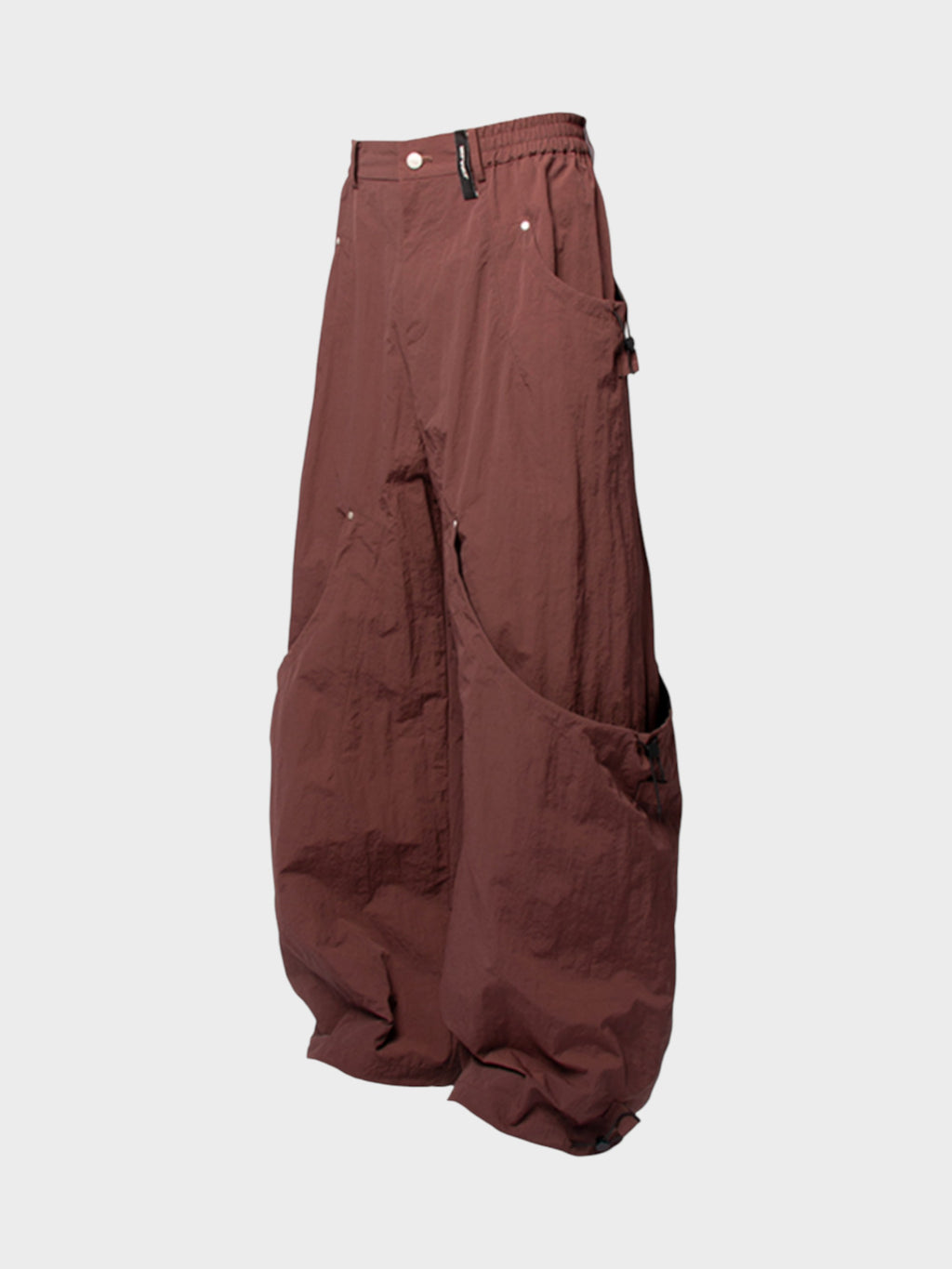 Pantalon cargo multi-poches zippées Relabel bordeaux en nylon, vue de trois quarts sur fond gris, silhouette ballon et détail cordons chevilles