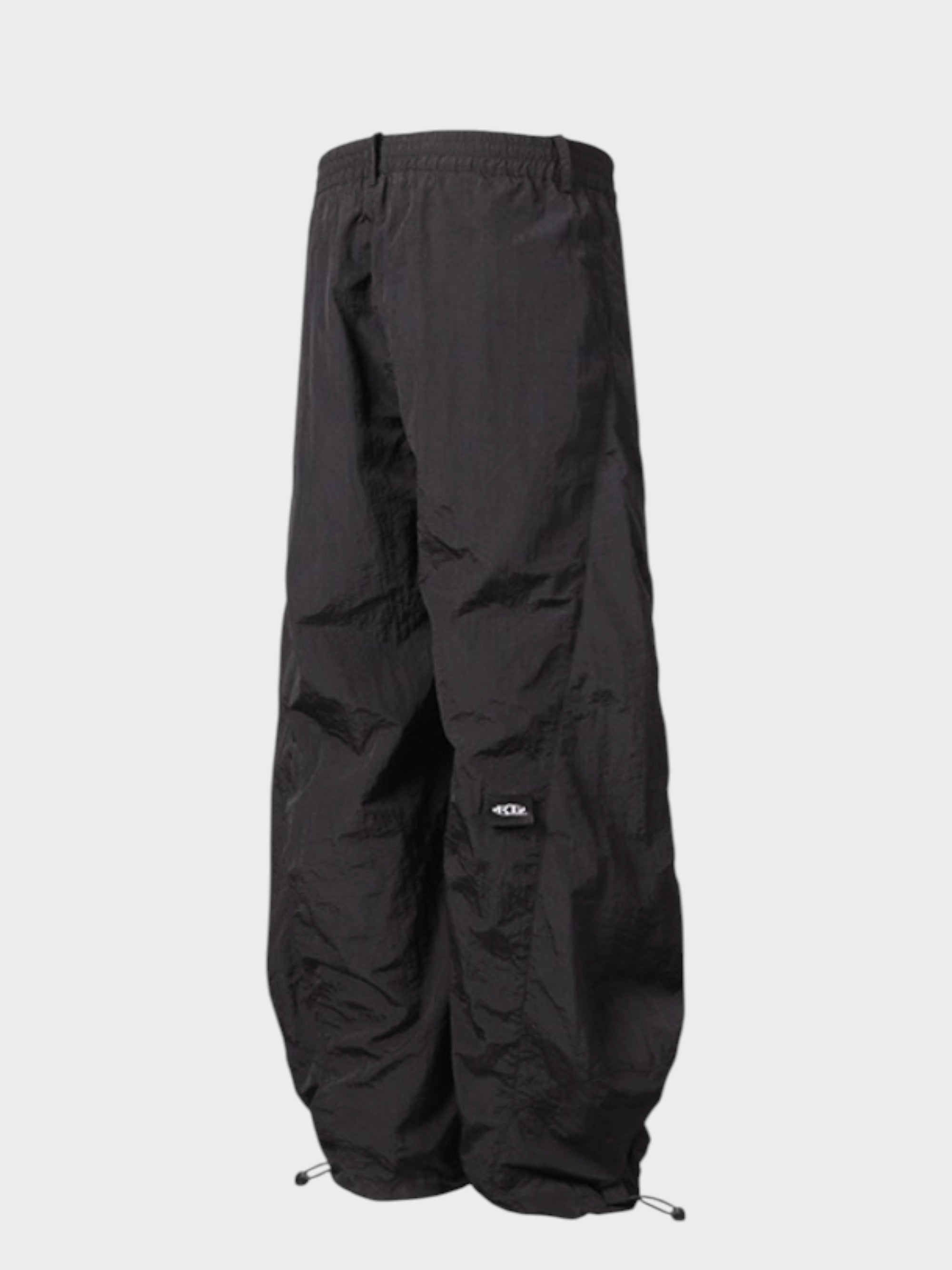 Pantalon cargo superposé avec jupe Relabel noir en nylon, vue de face sur fond gris, détail ceinture élastique, patch logo et cordons chevilles