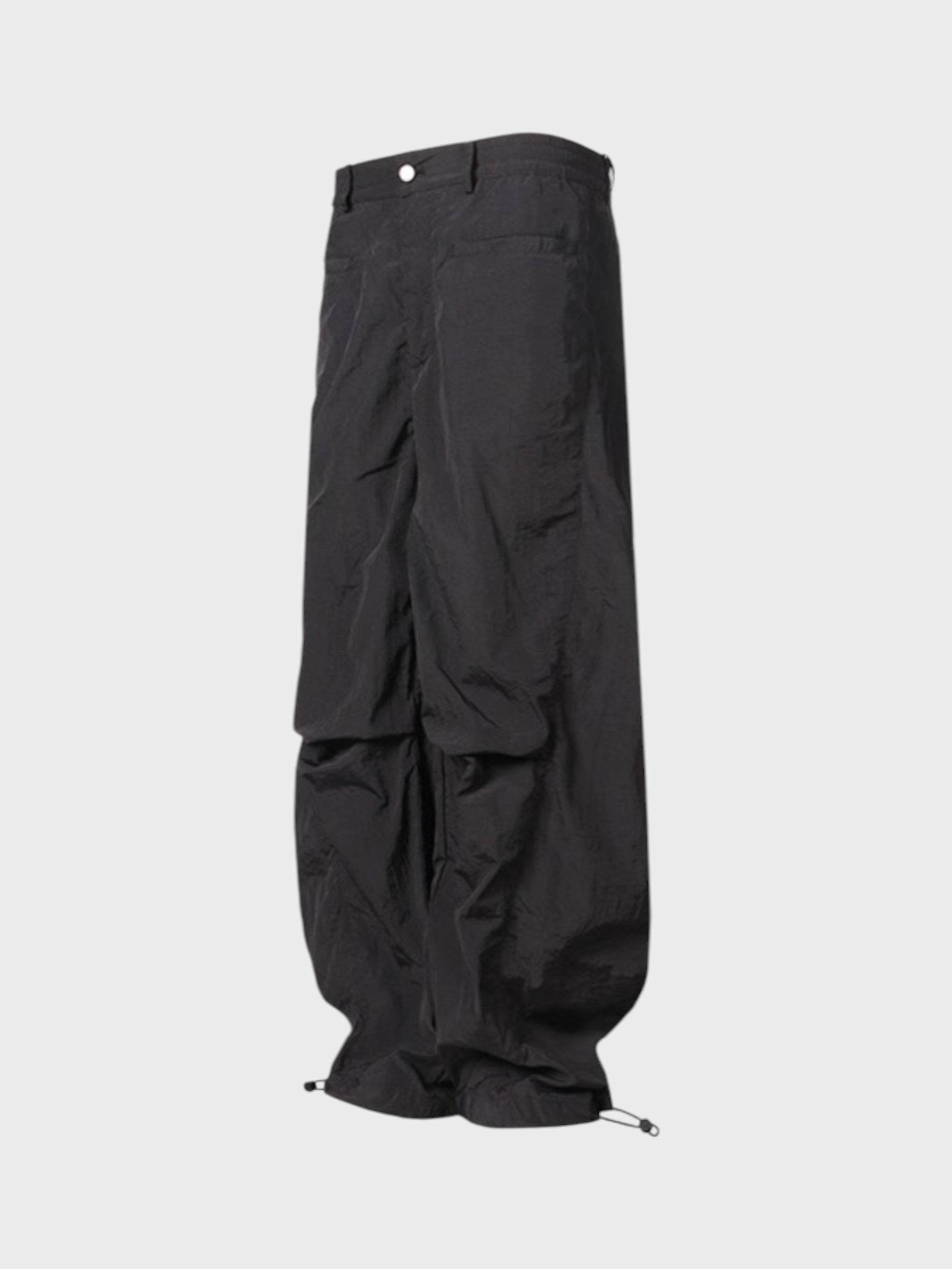 Pantalon cargo superposé avec jupe Relabel noir en nylon, vue de trois quarts sur fond gris, détail jupe évasée superposée et cordons chevilles