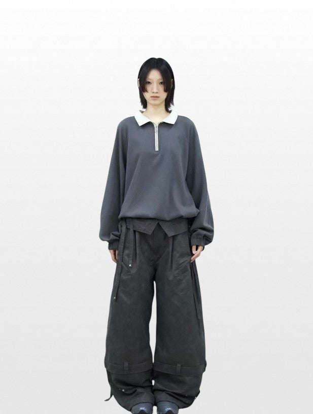 Sweat polo demi-zip oversize RELABEL gris col blanc porté par une femme, vue de face avec pantalon cargo large noir et sneakers noires
