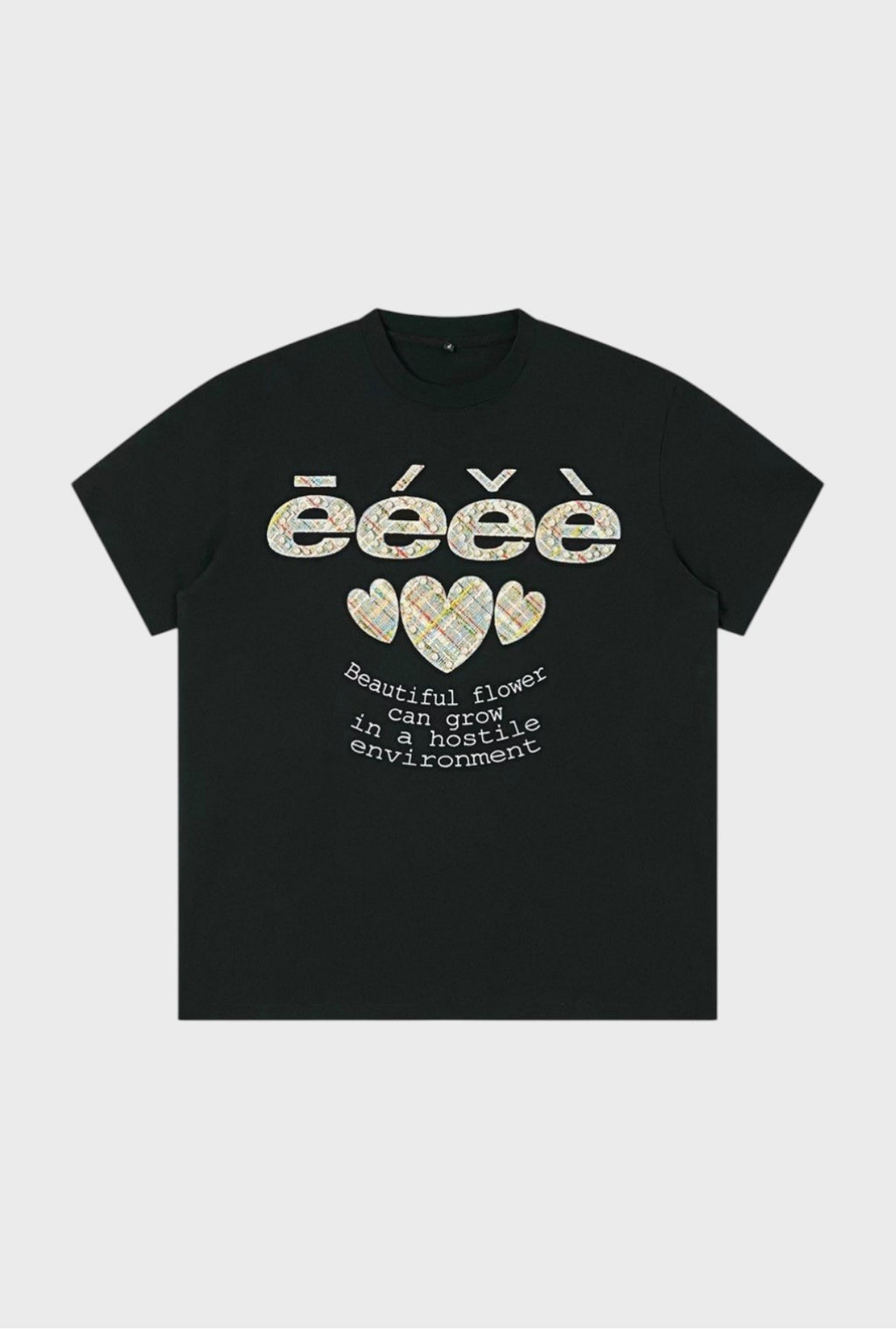 T-shirt oversize eeee Artmonster noir avec appliqués tweed multicolore logo eeee et trois cœurs perles, inscription "Beautiful flower can grow in a hostile environment", vue de face
