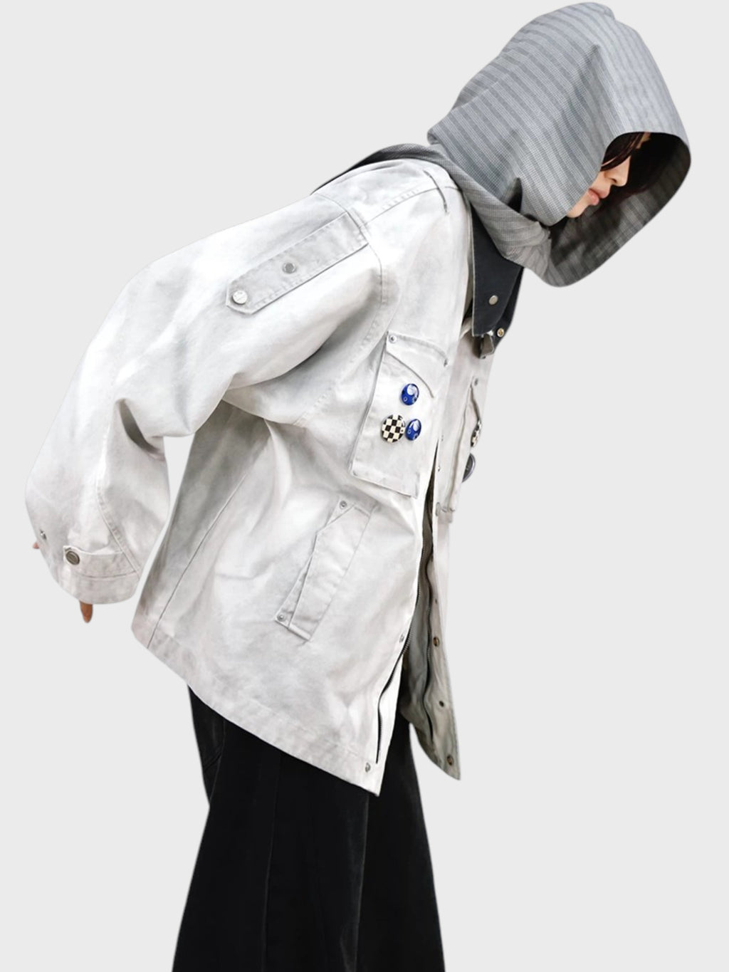 Veste M65 RELABEL blanc fumé washed portée par une femme de profil, capuche carreaux gris relevée avec badges décoratifs
