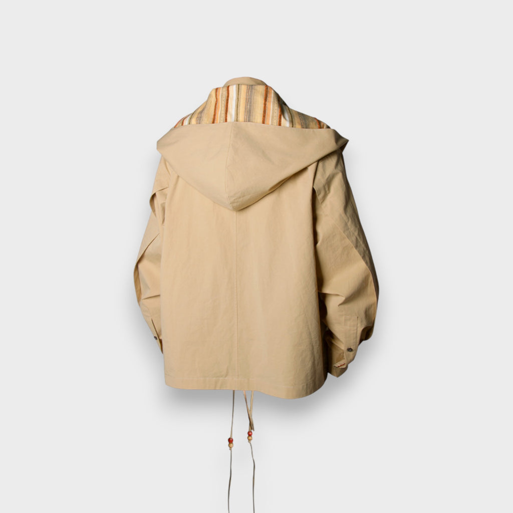 Veste à capuche oversize zippée Relabel beige en coton avec écharpe rayures multicolores intégrée, vue de dos sur mannequin fond gris, détail grande capuche drapée et cordons perles